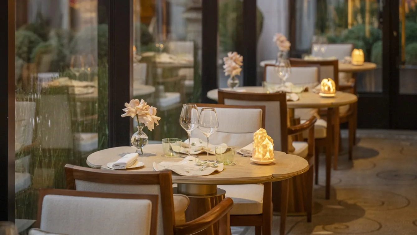 L'Orangerie, the two-Michelin-starred restaurant under its glass canopy overlooking the hotel's marble courtyard.