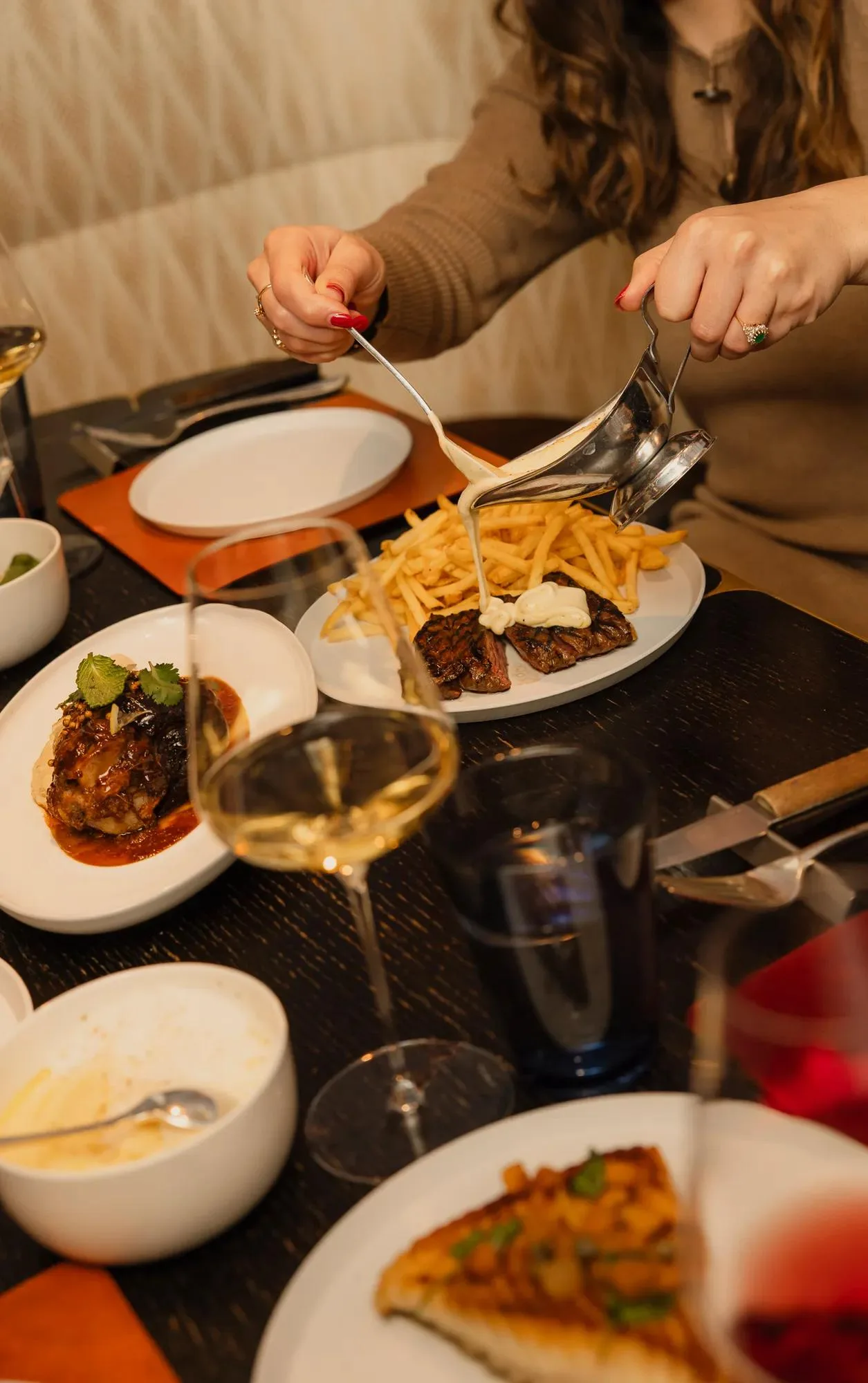 A steak-frites dish being finished tableside at Nonos & Comestibles par Paul Pairet, Hôtel de Crillon.