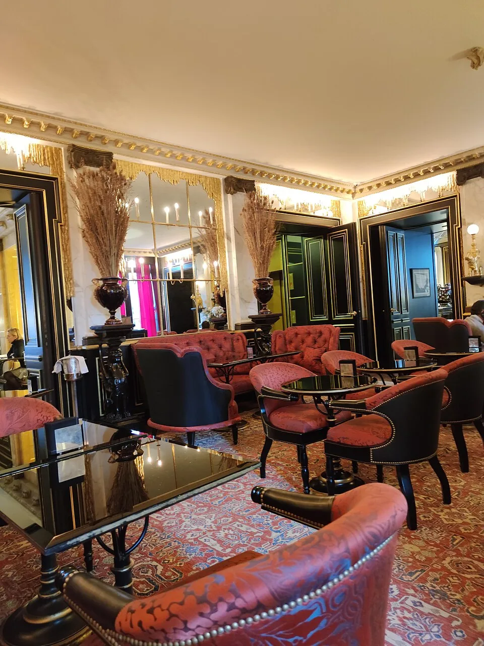 La Réserve Paris's bar, with black lacquer panelling, gilt trim and deep red upholstery.