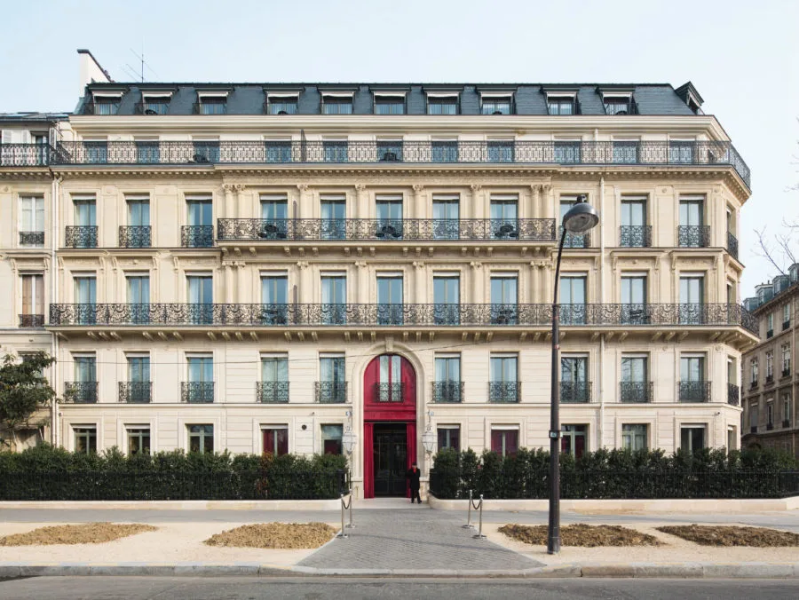La façade de style hôtel particulier de La Réserve Paris et sa porte rouge emblématique.
