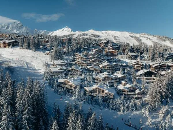 Vue aérienne des chalets du Le K2 Palace éparpillés à flanc de colline parmi les pins.