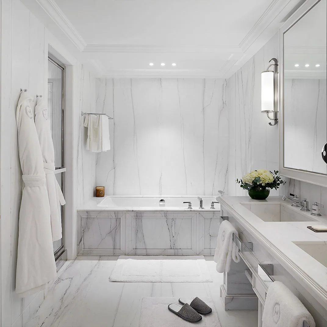 A marble bathroom with a deep soaking tub and a dedicated vanity counter.