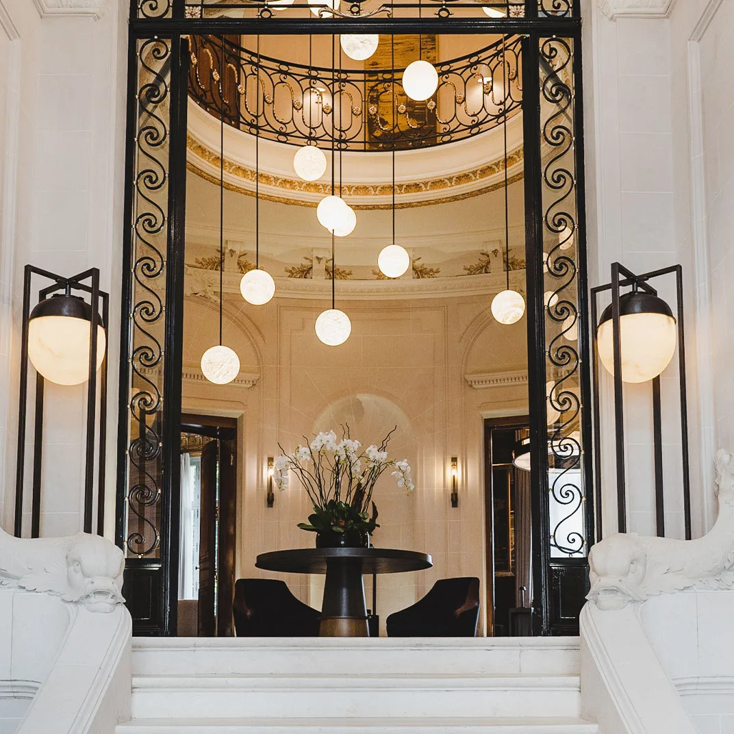 The mansion's original stairwell, framed by a mirrored doorway and hanging glass-globe lights.