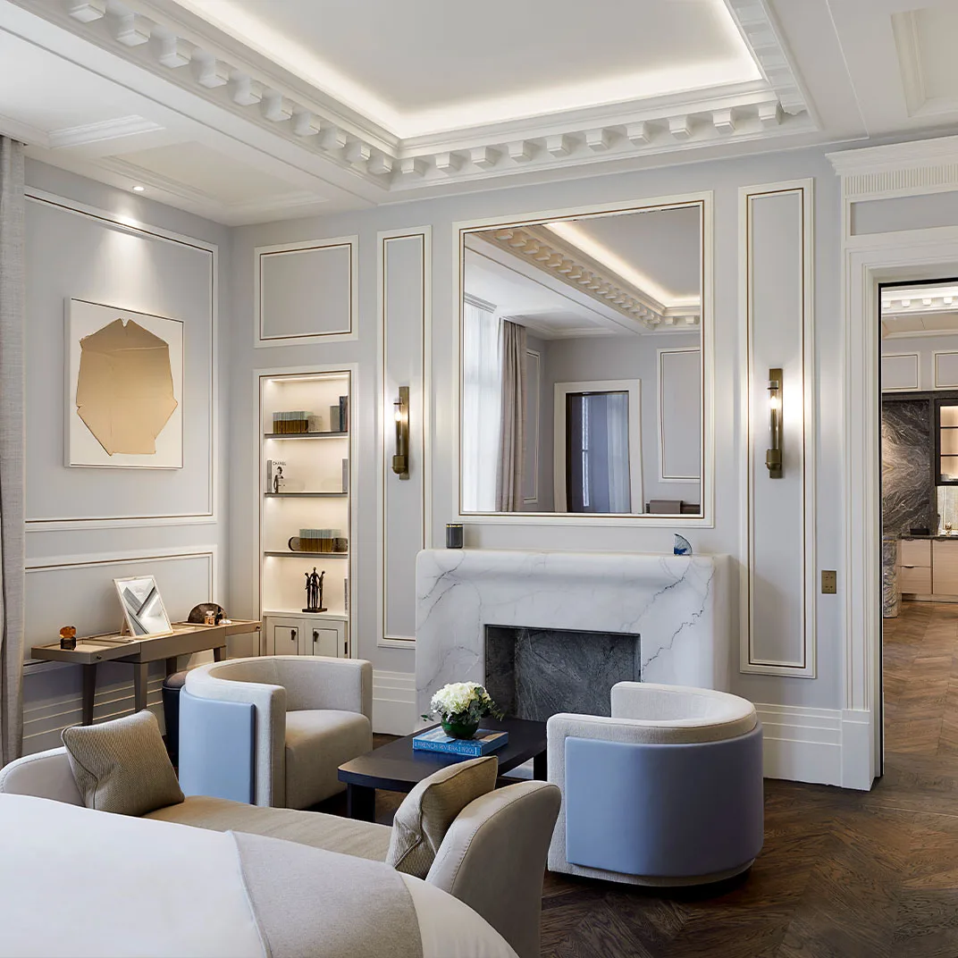 A suite living room with a marble fireplace and its own dressing room visible through the doorway.