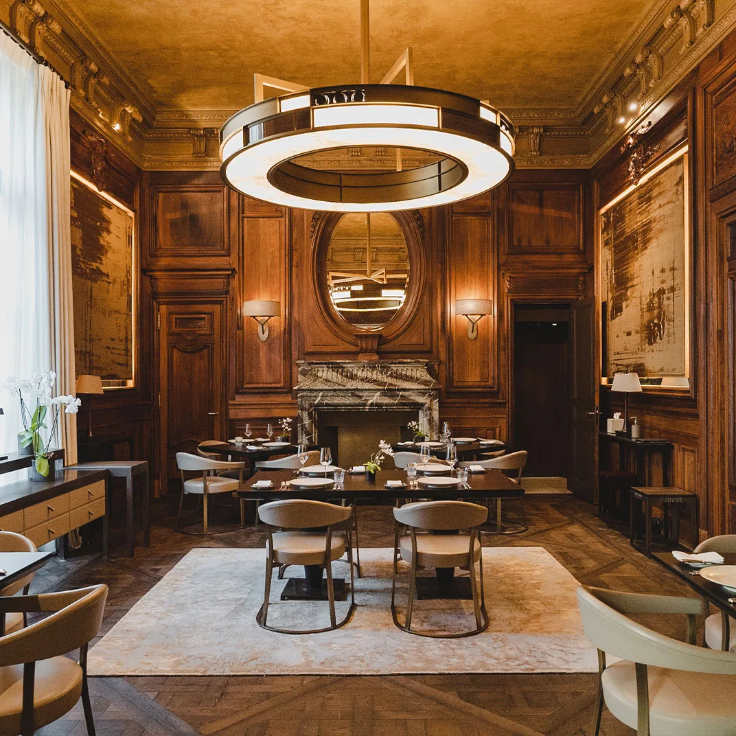 Trente-Trois's wood-panelled dining room, tables set beneath a carved marble fireplace mirror.