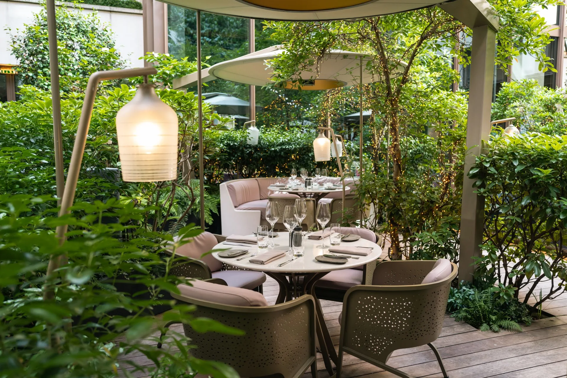 Camélia's lush garden terrace, set for dinner beneath string lights.