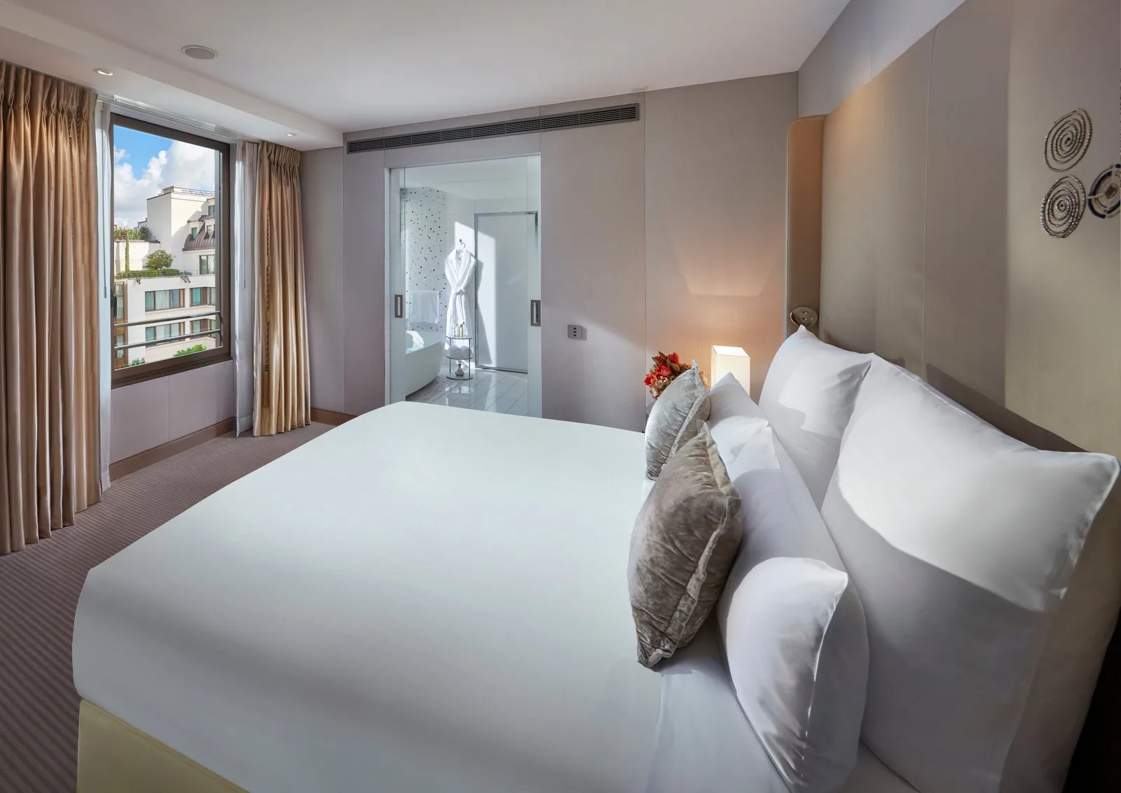 The bedroom of a Couture Suite, with a garden view and an adjoining marble bathroom.