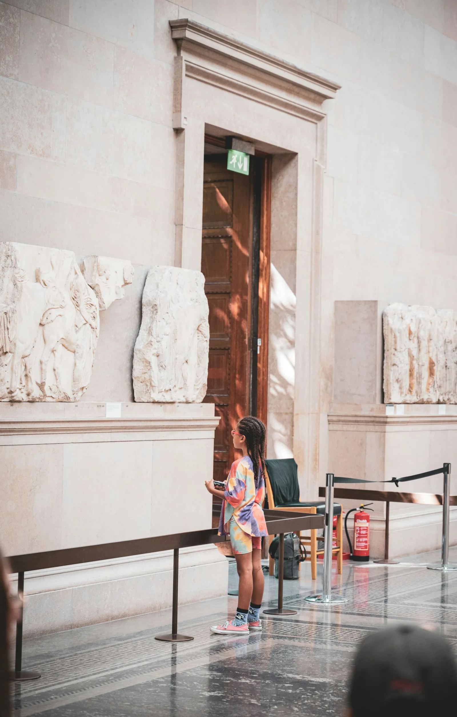 A child looking closely at ancient marble relief sculptures in a museum gallery.
