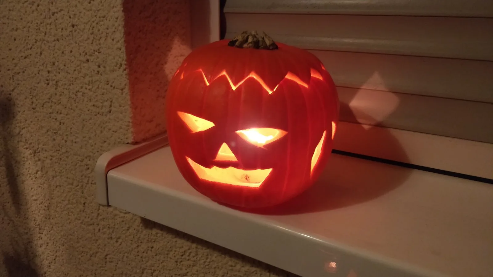 Une citrouille d'Halloween éclairée sur un rebord de fenêtre.