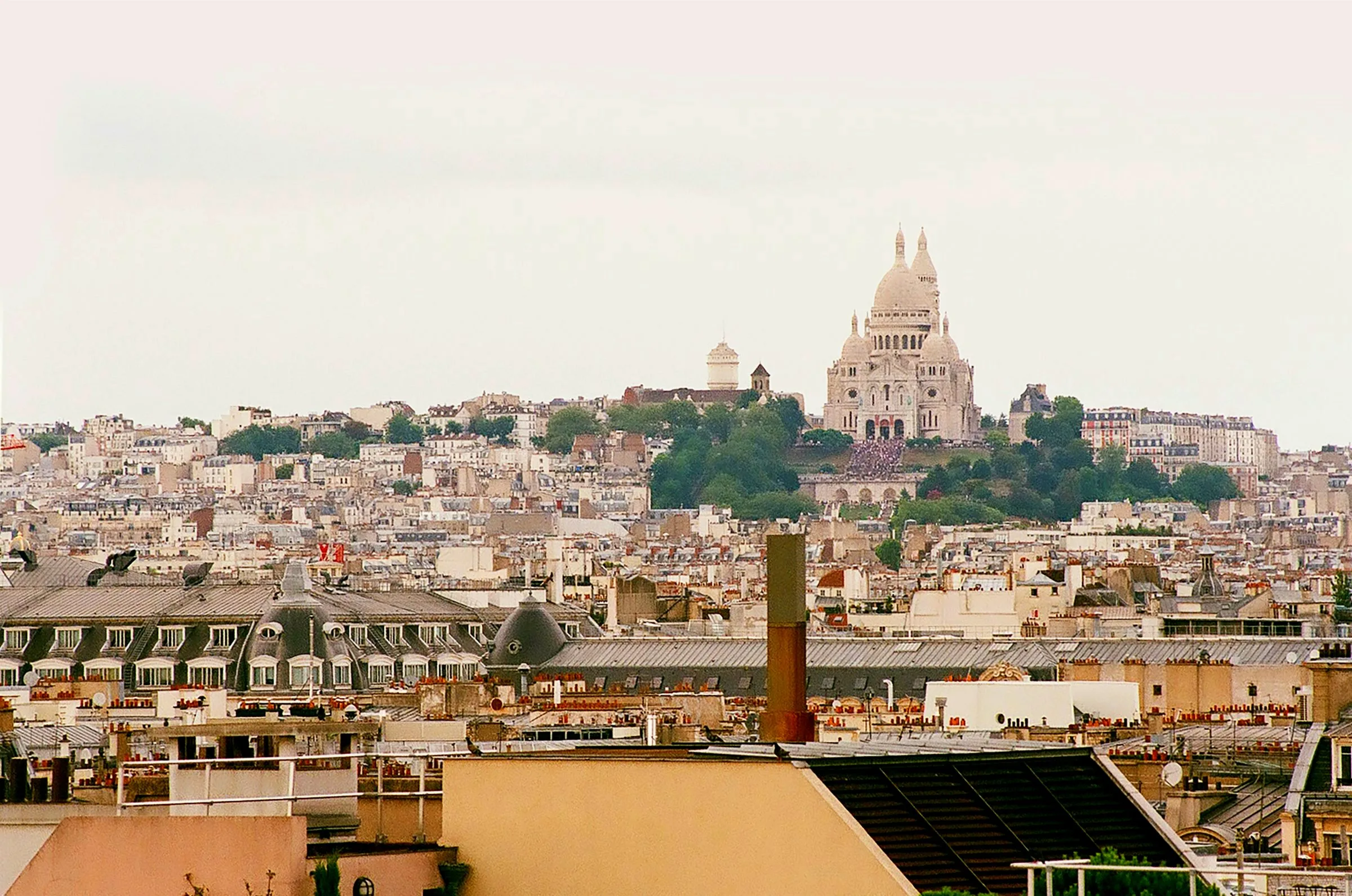 Paris rooftops with the Sacré-Cœur basilica in the distance.