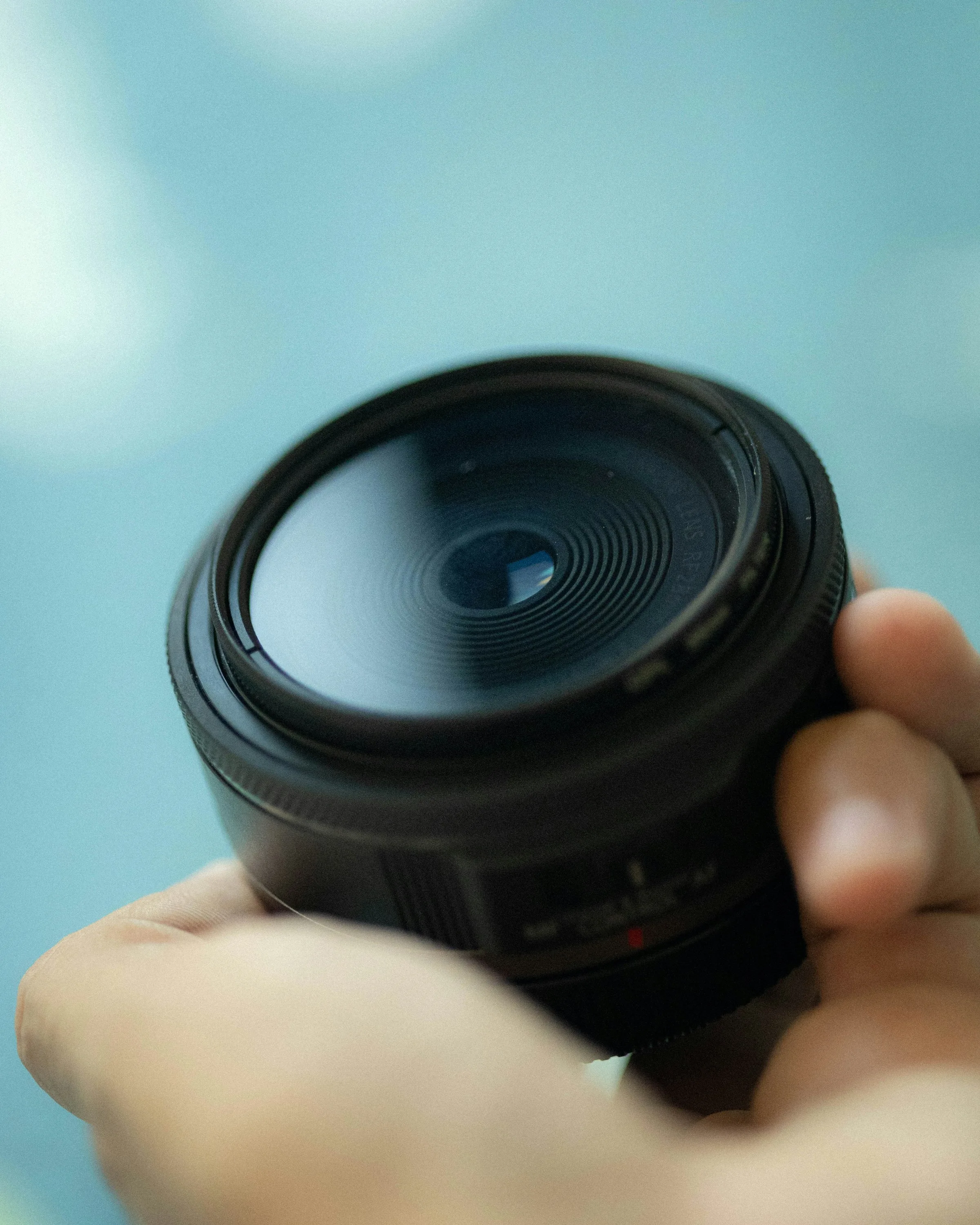 A hand holding a camera lens, close up.