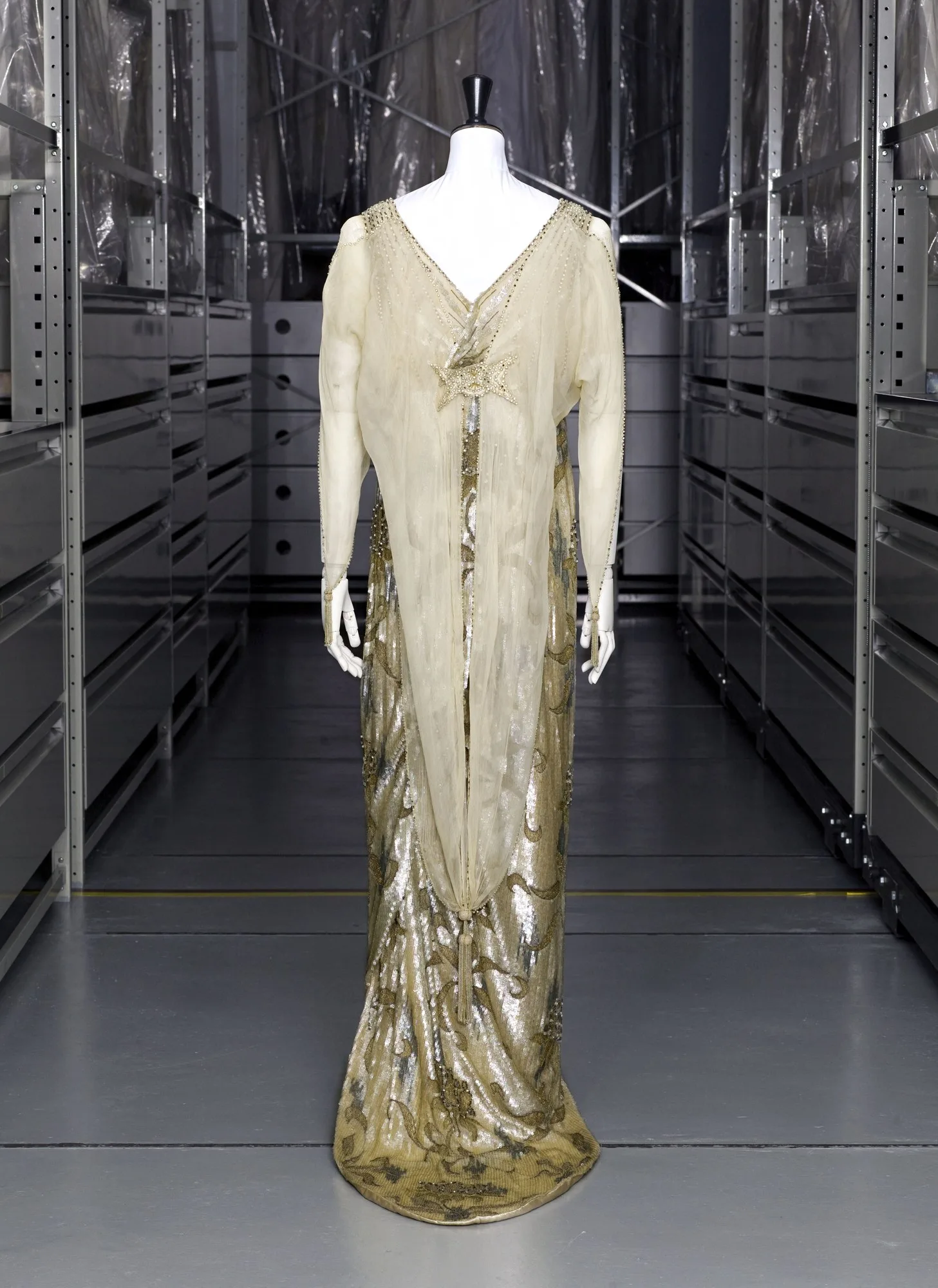 Une robe du soir dorée des collections du Palais Galliera, présentée sur un mannequin dans une réserve de musée.