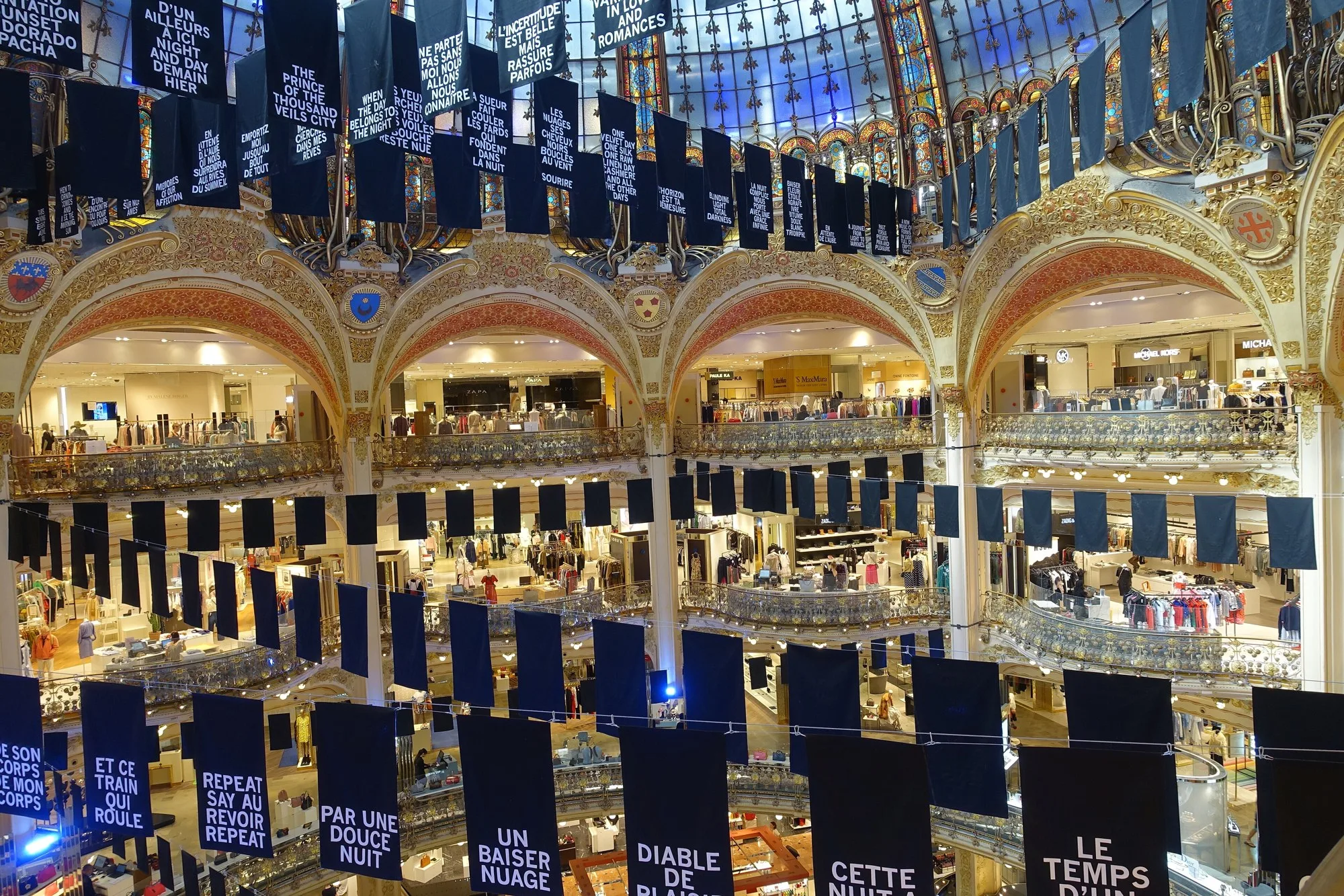 La coupole en vitrail et les balcons d'un grand magasin parisien vus d'en bas.