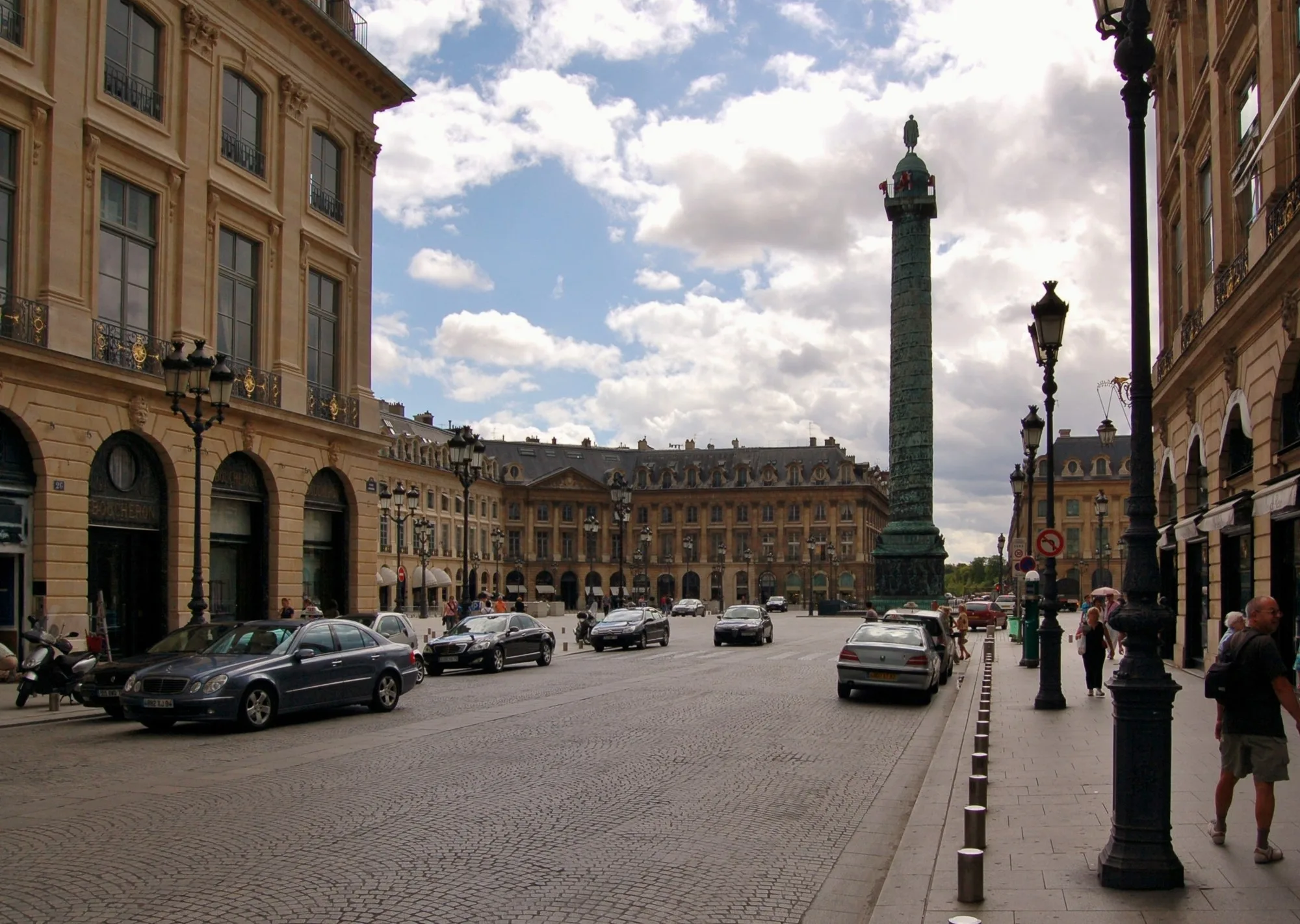 La place Vendôme à Paris, la colonne au centre et les façades à arcades sous un ciel nuageux.