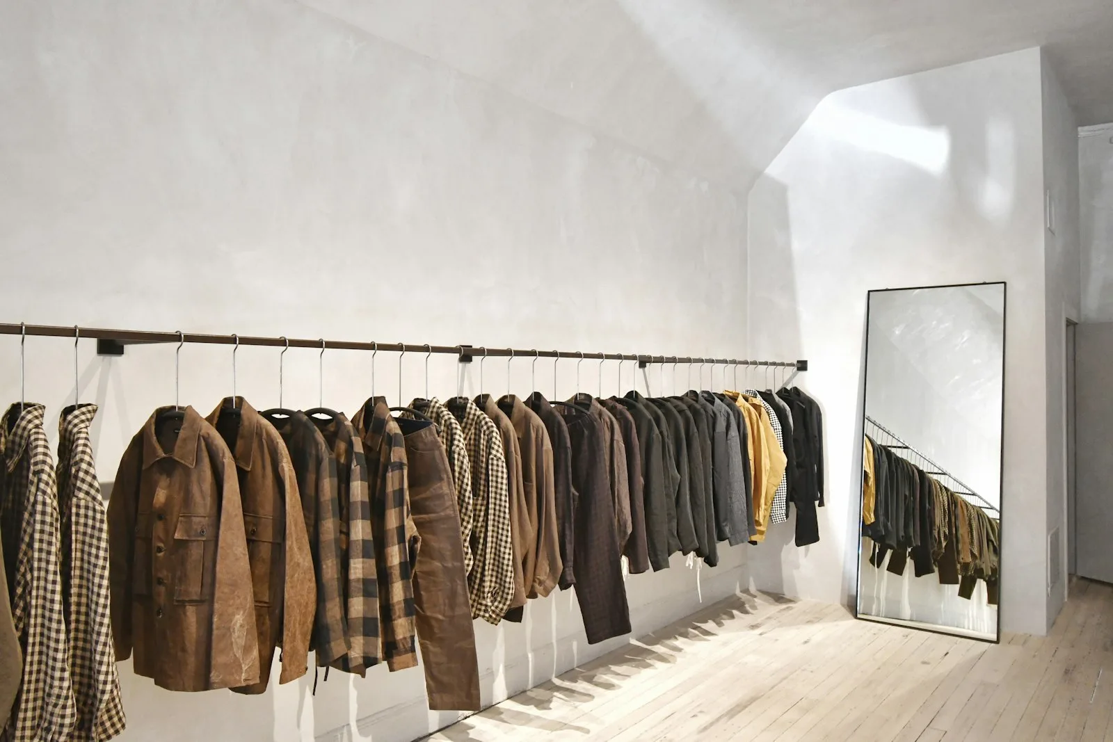 A minimalist clothing boutique with a wall of garments on hangers.