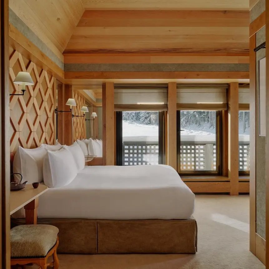 Suite La Vanoise 套房主卧,木质室内装饰,玻璃门外是雪山景观。