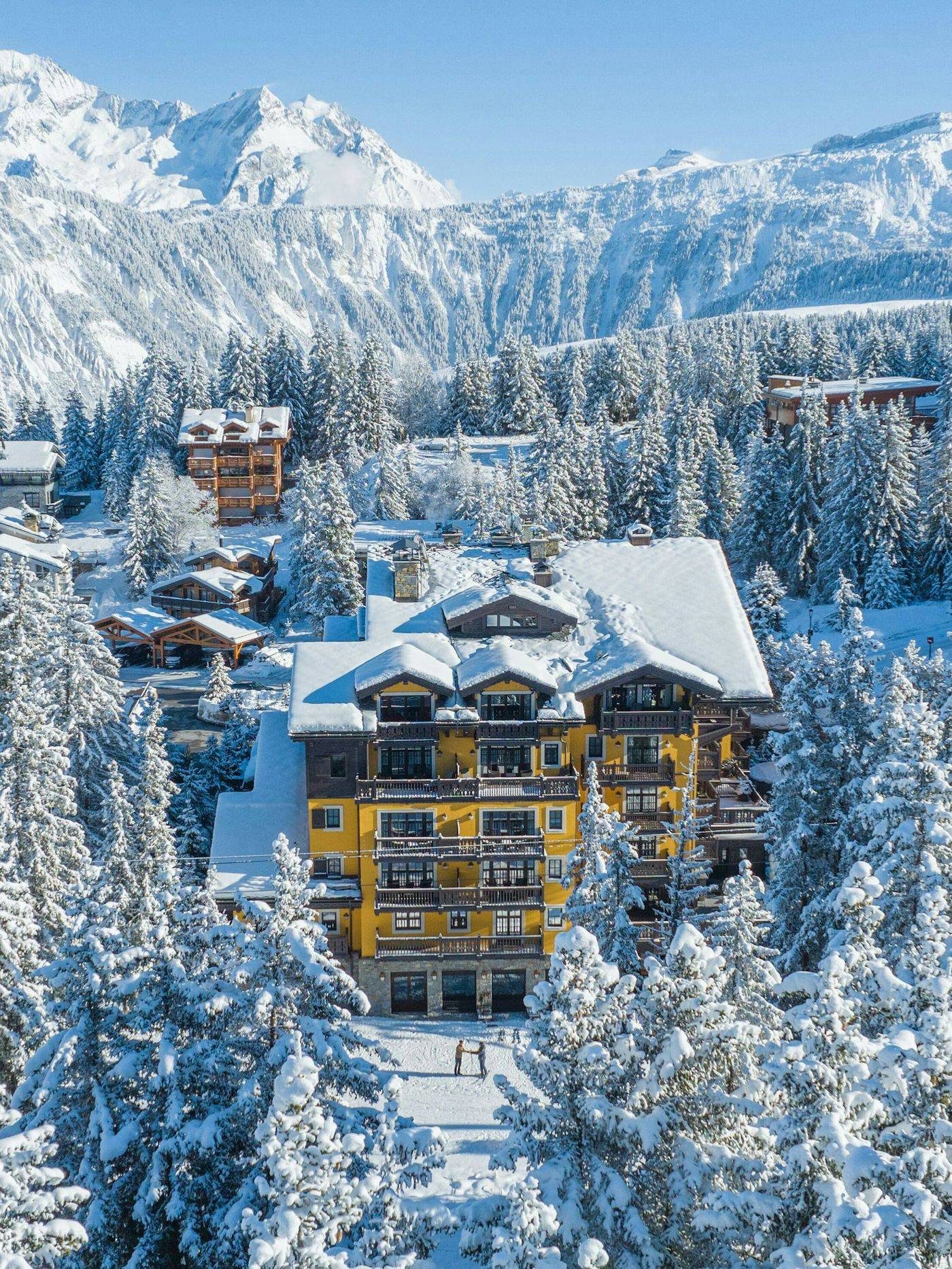 Cheval Blanc Courchevel 黄色木屋航拍，四周是积雪的松林