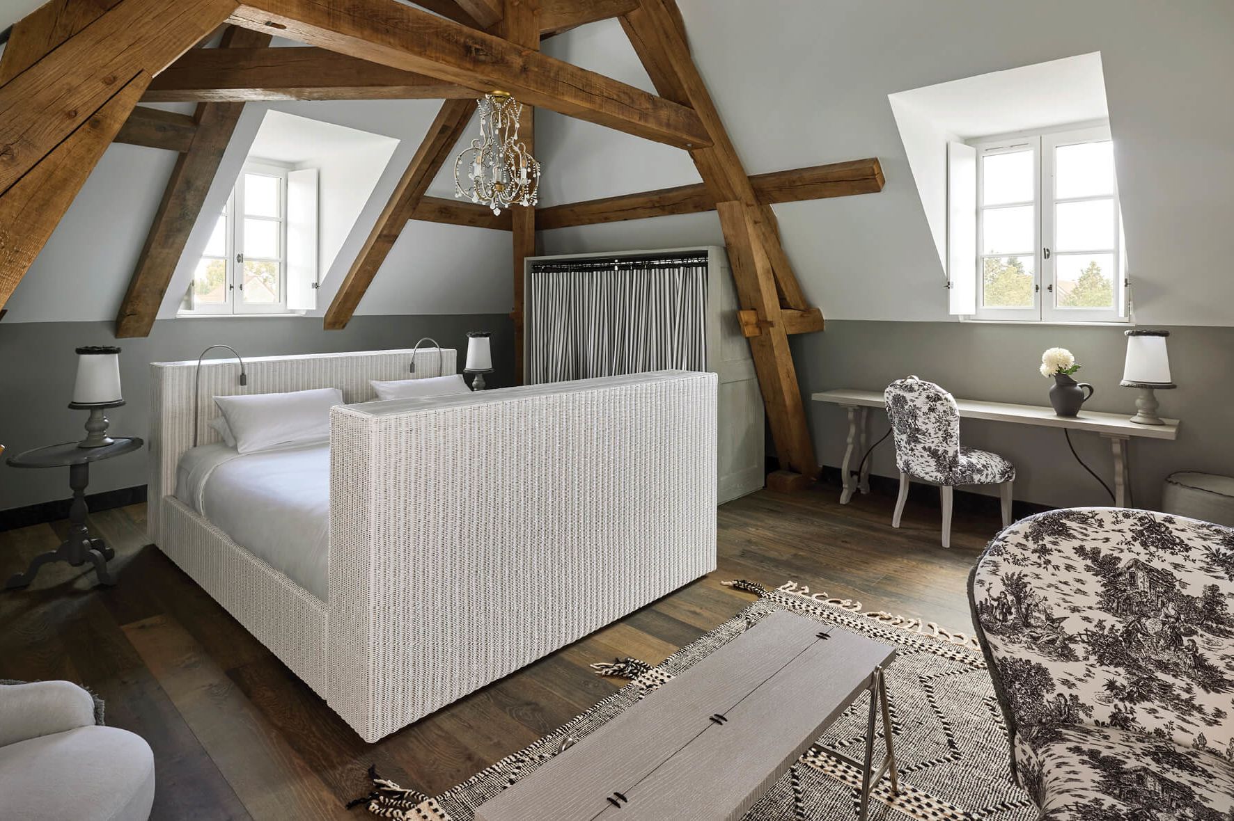 A Manoir room under the eaves, with original oak beams and toile de Jouy upholstery.