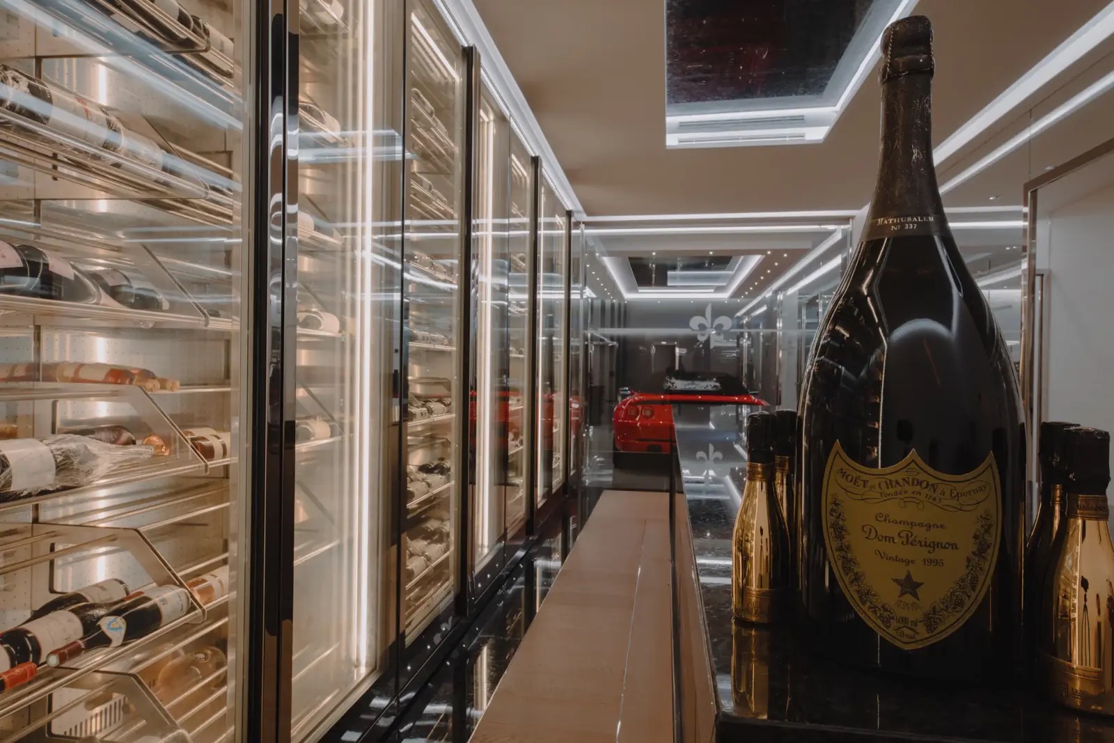 The villa’s wine cellar, with illuminated glass racks and a sports car visible through the garage window.