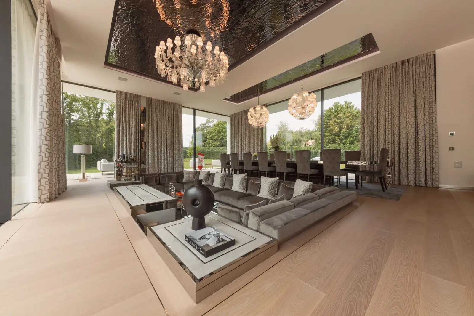 The sunken living and dining room, seating a large group beneath a pair of chandeliers.