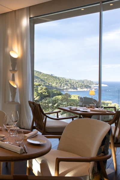 La Voile's dining room, floor-to-ceiling glass framing the coastline below.