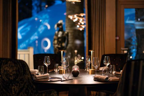 A table set at L’Altiplano, Le K2 Palace’s two-Michelin-starred Peruvian restaurant, with the night piste visible through the window.