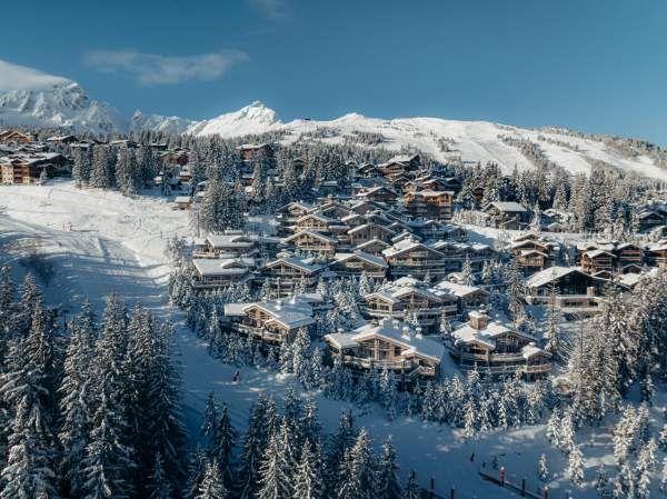 An aerial view of Le K2 Palace’s chalets spread across the hillside among the pines.