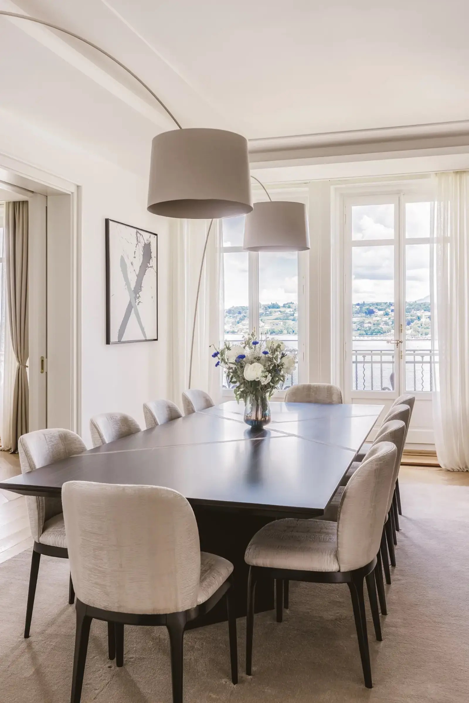La salle à manger du duplex, avec ses lampadaires arqués et sa vue sur le lac Léman.