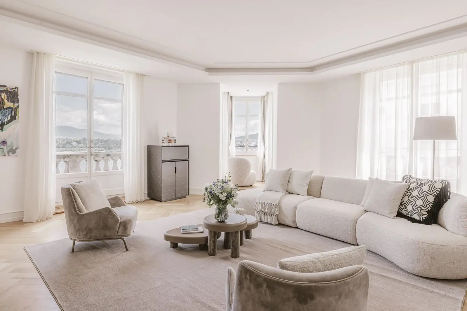 Le salon du duplex, avec vue sur le lac et les Alpes à travers de hautes fenêtres à la française.