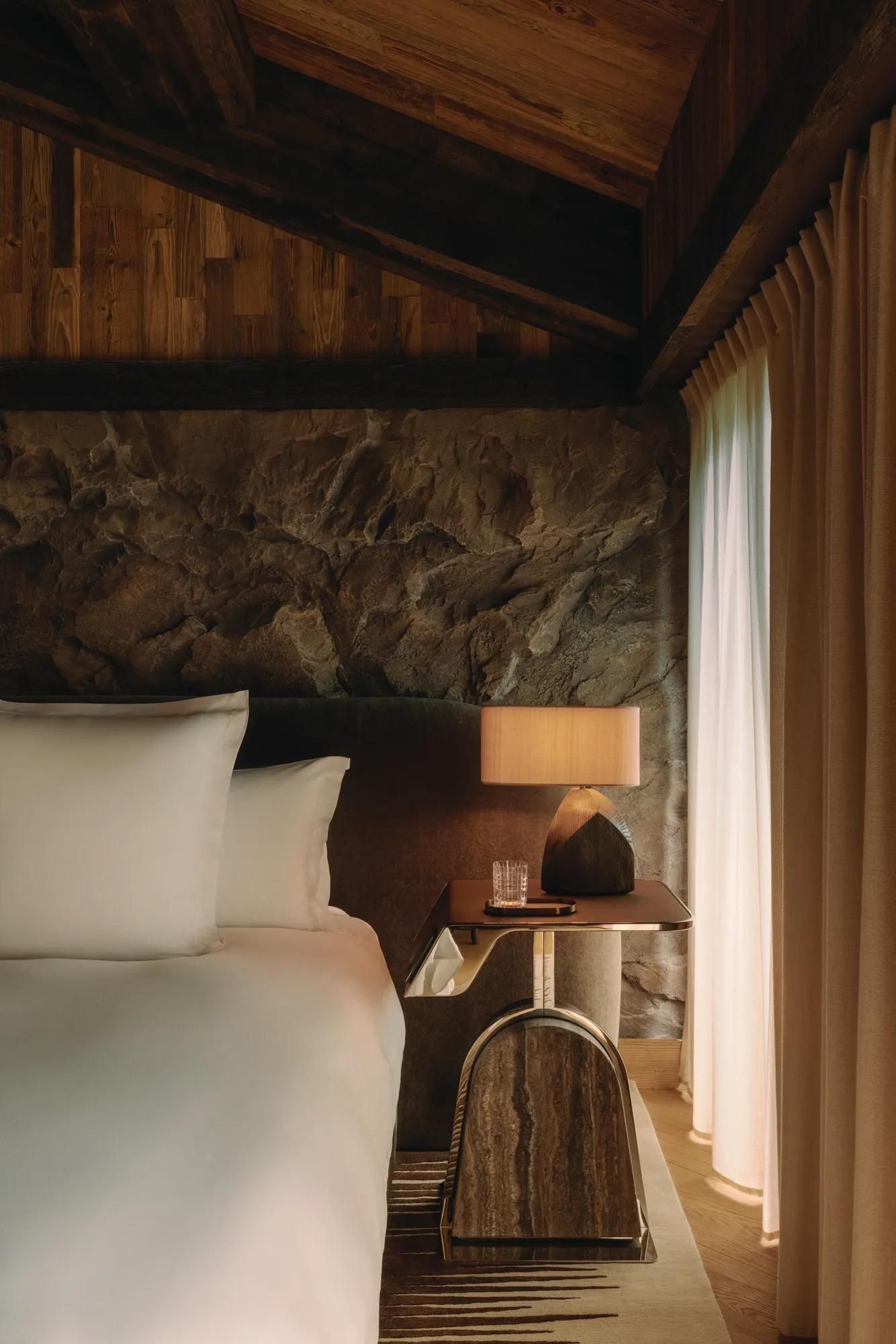 Rosewood Courchevel Le Jardin Alpin 的一间卧室，床头石墙在台灯下泛着暖光