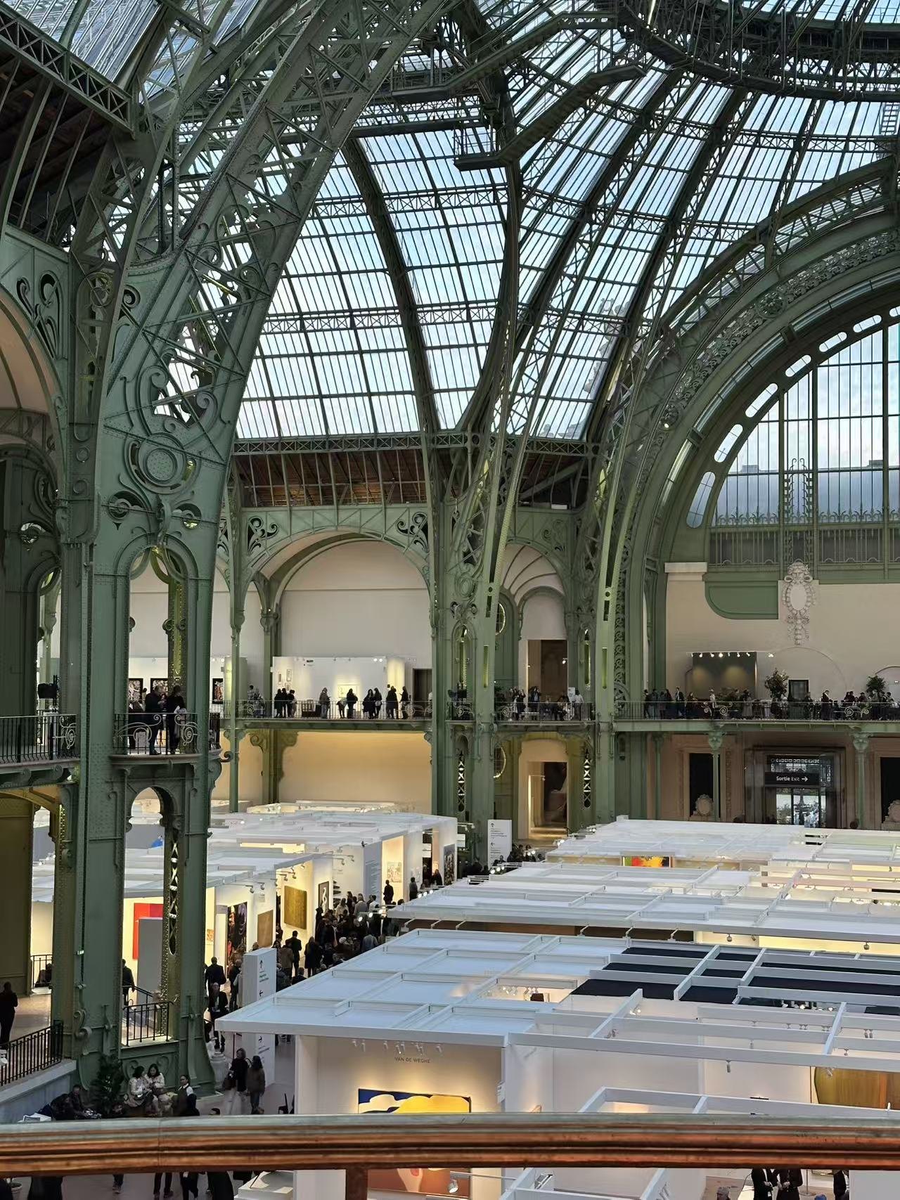 从阳台看展厅,在 Grand Palais 绿色铁屋顶下,参观者在展位之间走动