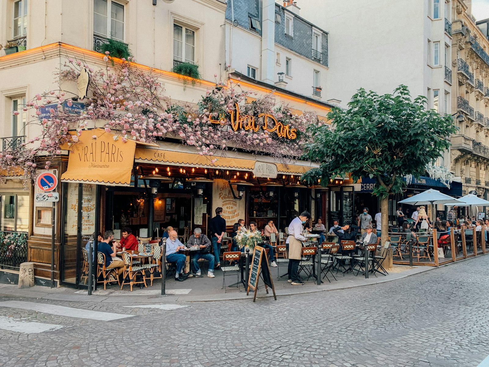 Des personnes assises à la terrasse d'un café, dans une rue de Paris.