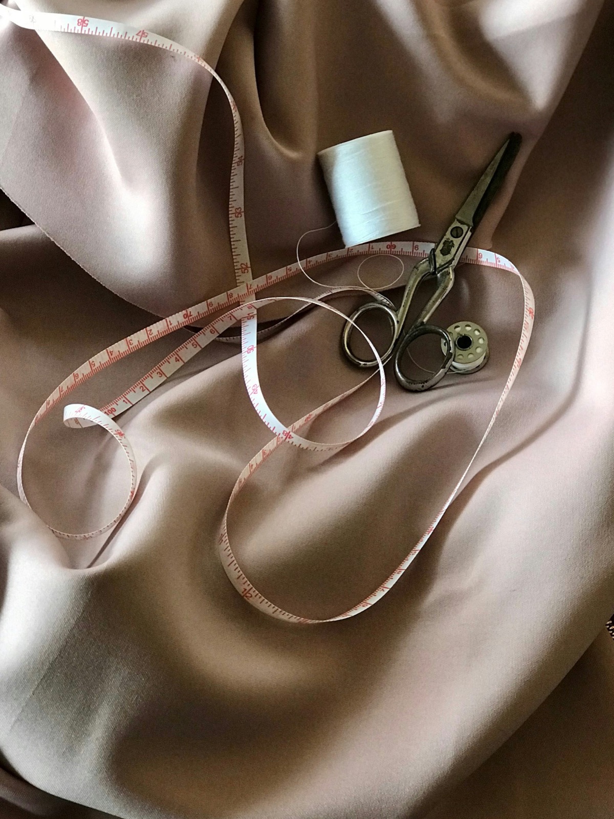 Un mètre ruban de couturier et des ciseaux sur un tissu de soie fine.