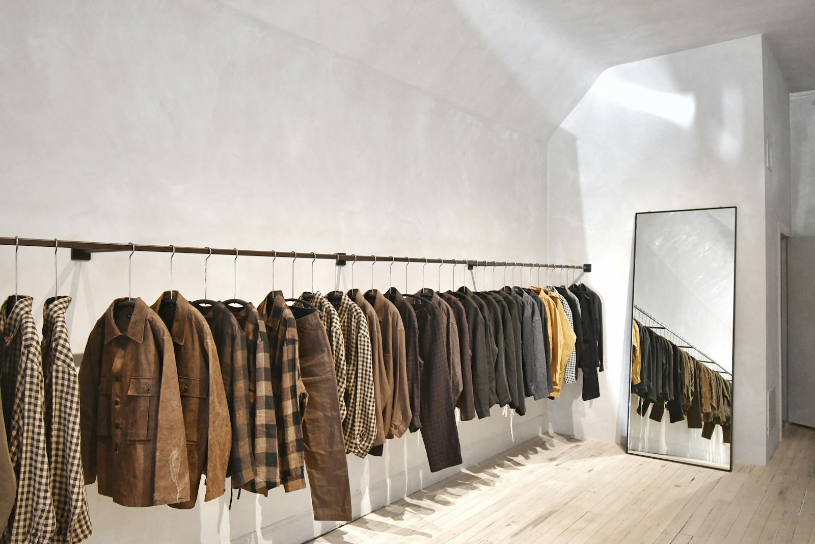 A minimalist clothing boutique with a wall of garments on hangers.