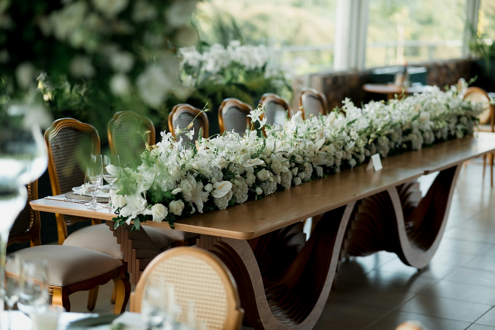A long table dressed with an elaborate arrangement of white flowers.
