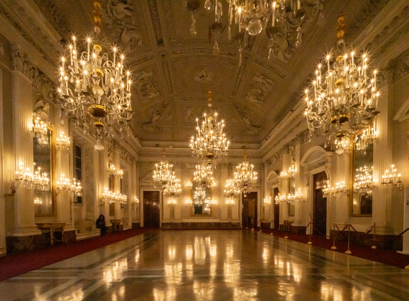 A grand ballroom lit by rows of crystal chandeliers.