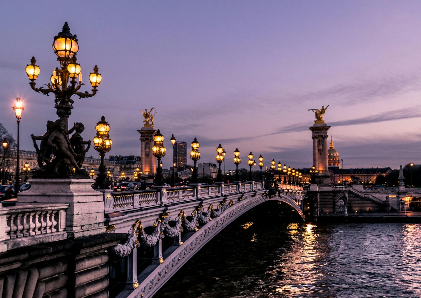 Pont Alexandre III at dusk, its ornate lampposts lit above the Seine.