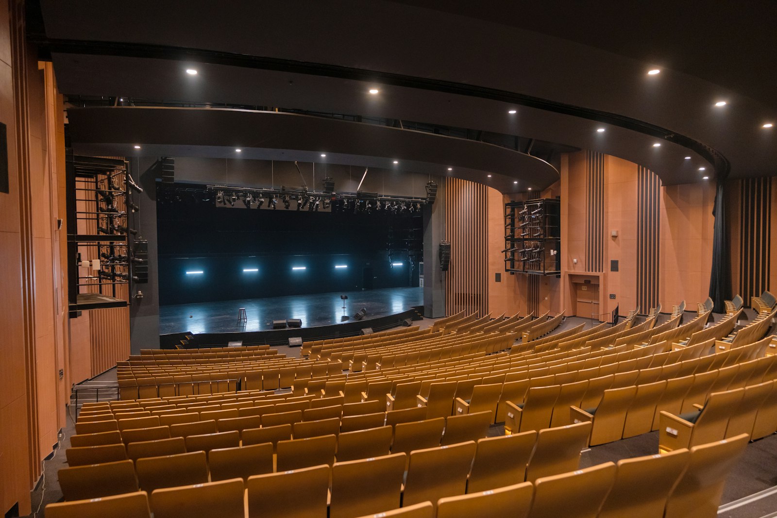 An empty theatre auditorium with rows of red seats facing the stage.