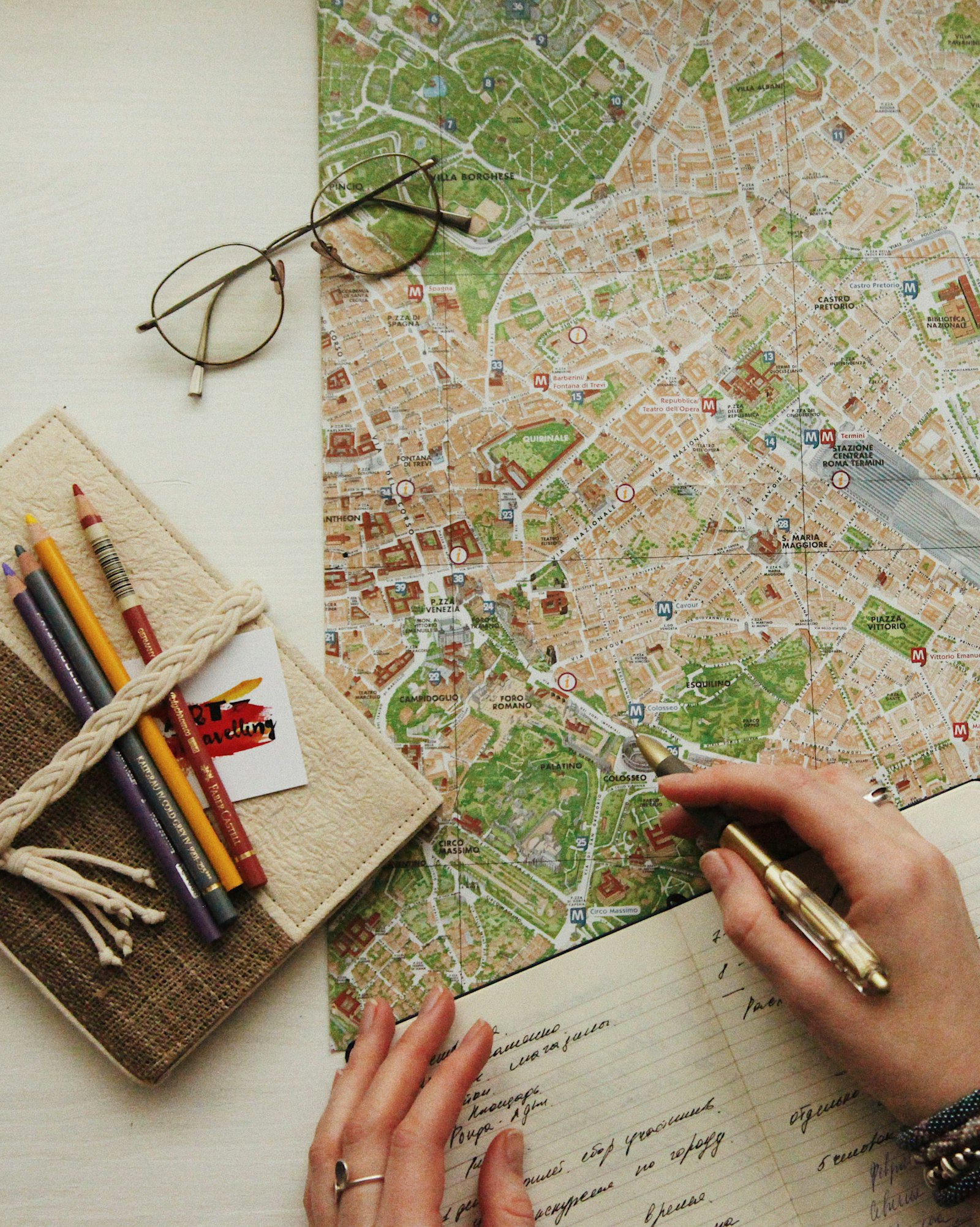A pair of glasses resting on an open travel map with a notebook and pen.